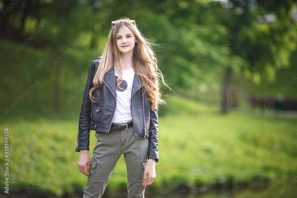 portrait of little beautiful stylish kid girl in city park on green forest background portrait of little beautiful stylish kid girl in city park on green forest background