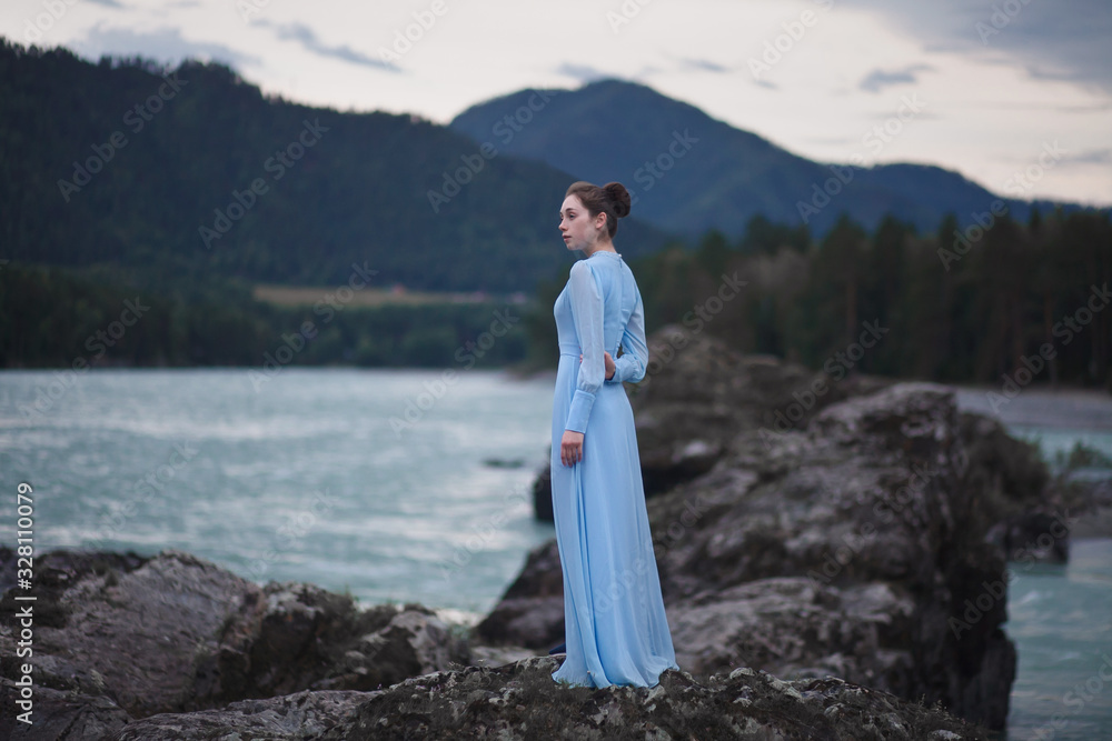 A girl in a blue dress stands on the banks of the river. A girl in a blue dress stands on the banks of the river.