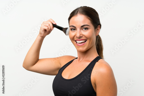 Young woman over isolated white background with makeup brush