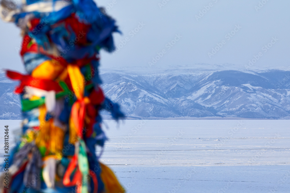Ribbons tied on a pole against the background of mountains and lake Baikal