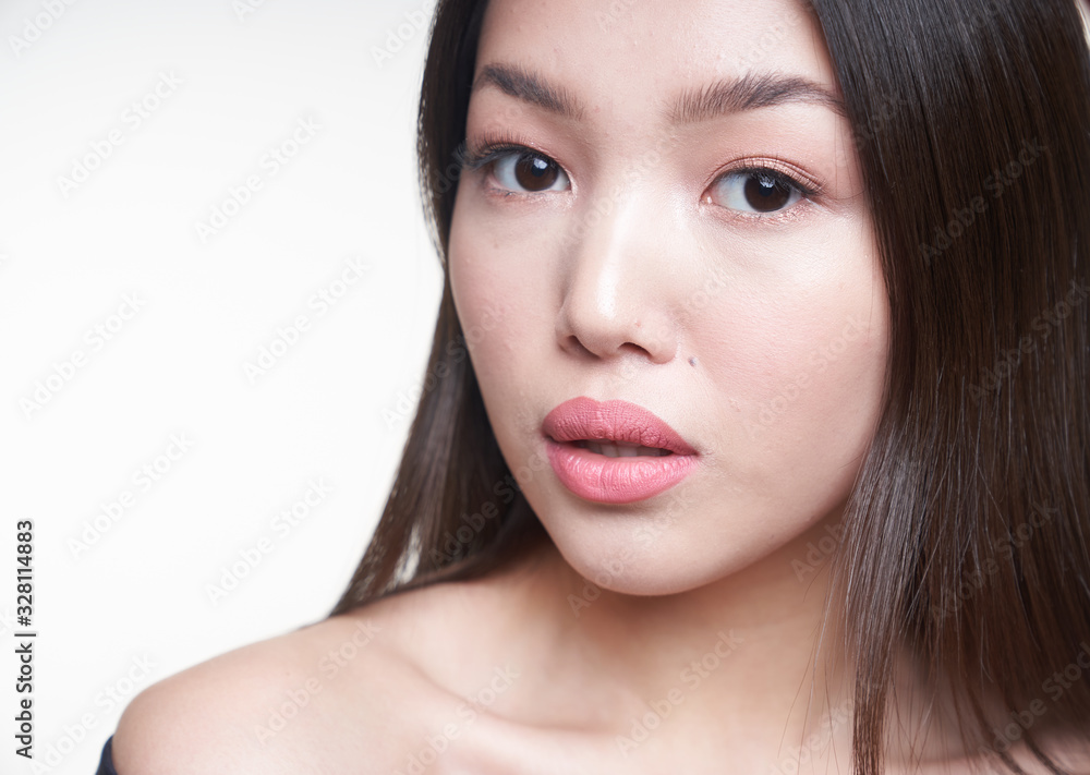 Close-up portrait of a young beautiful Asian girl, looking directly at the camera, dressed in a blue jacket. The concept of care of skin and hair Close-up portrait of a young beautiful Asian girl, looking directly at the camera, dressed in a blue jacket. The concept of care of skin and hair