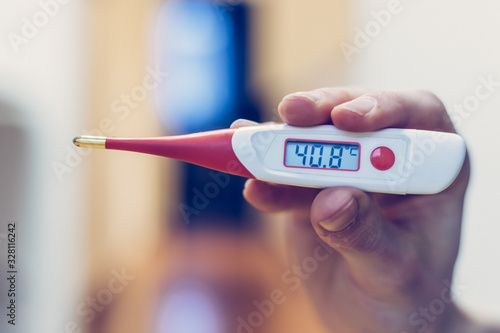 Flu and corona concept: Man is holding a fever thermometer in his hand, close up photo