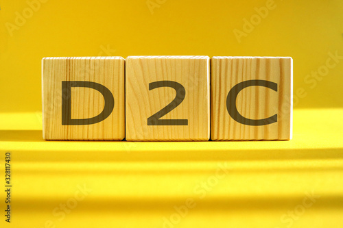 D2C word made of wooden cubes on a yellow background, business concept.