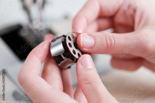 The hands of a master and the needle of a leather product sewing on a sewing machine. Manual work, business.