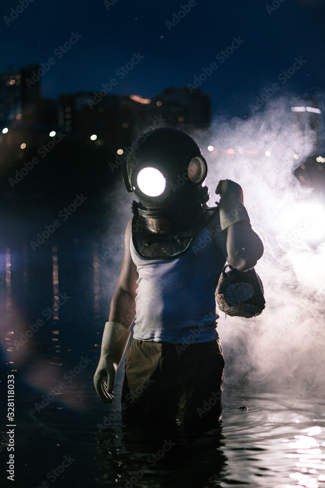 Fototapeta premium Diver with garbage stands on a background of sunset in the water.