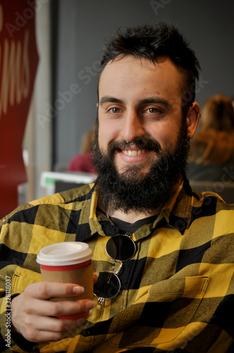 Young man drinking coffee in a coffee shop early in the morning/ having a big smile