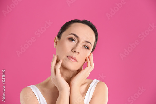 Portrait of beautiful mature woman on pink background