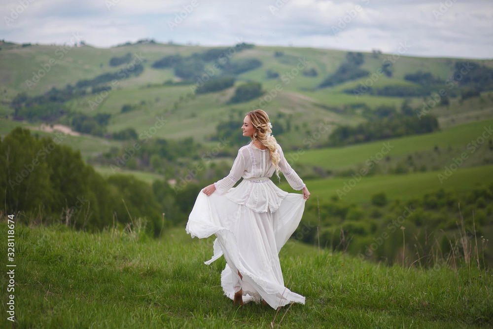 the bride walks in the field against the backdrop of the mountain