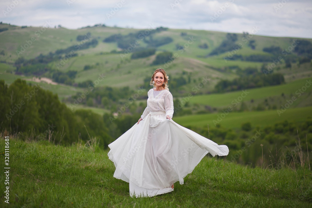 the bride walks in the field against the backdrop of the mountain