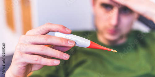 Flu and corona concept: Man is holding a fever thermometer in his hand, close up