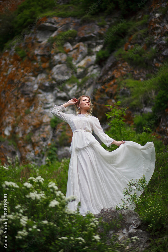 Fototapeta premium the bride walks in the field against the backdrop of the mountain