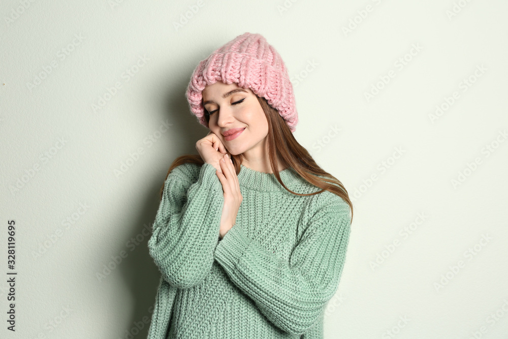 Young woman wearing warm sweater and hat on light background. Winter season Young woman wearing warm sweater and hat on light background. Winter season