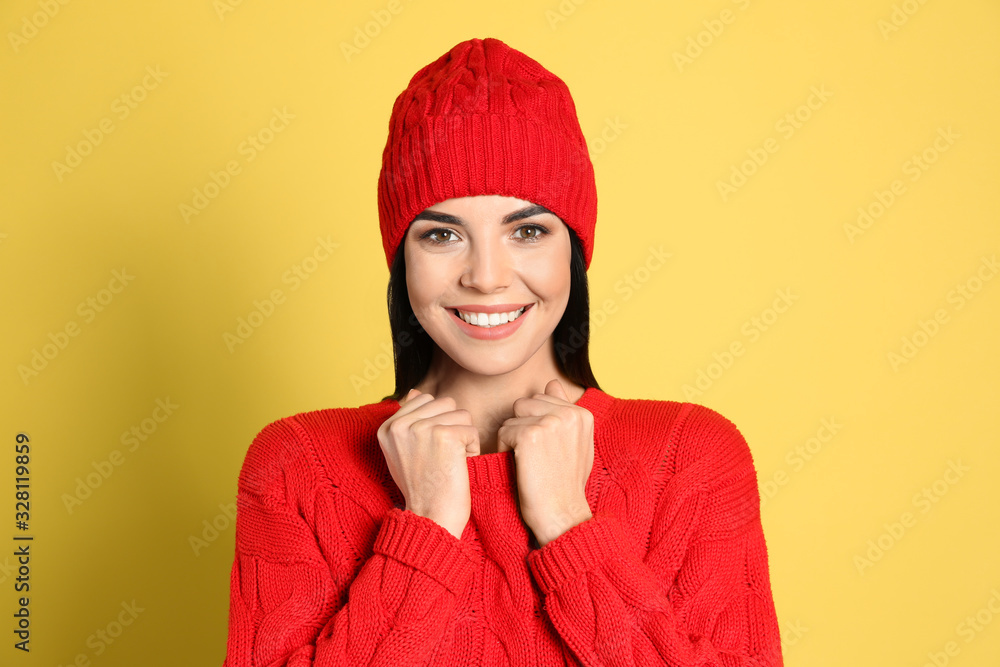 Young woman wearing warm sweater and hat on yellow background. Winter season Young woman wearing warm sweater and hat on yellow background. Winter season