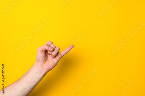 pinkie. keeping promise sign. little finger of male hand against yellow background with copy space for advert photo