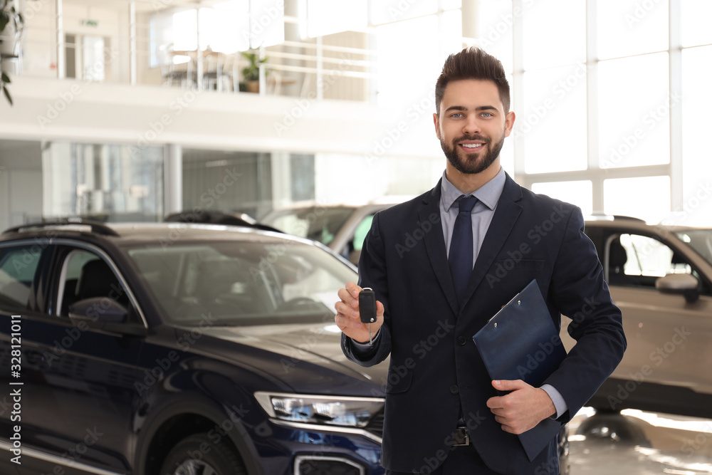 Salesman with key and clipboard in car salon Salesman with key and clipboard in car salon