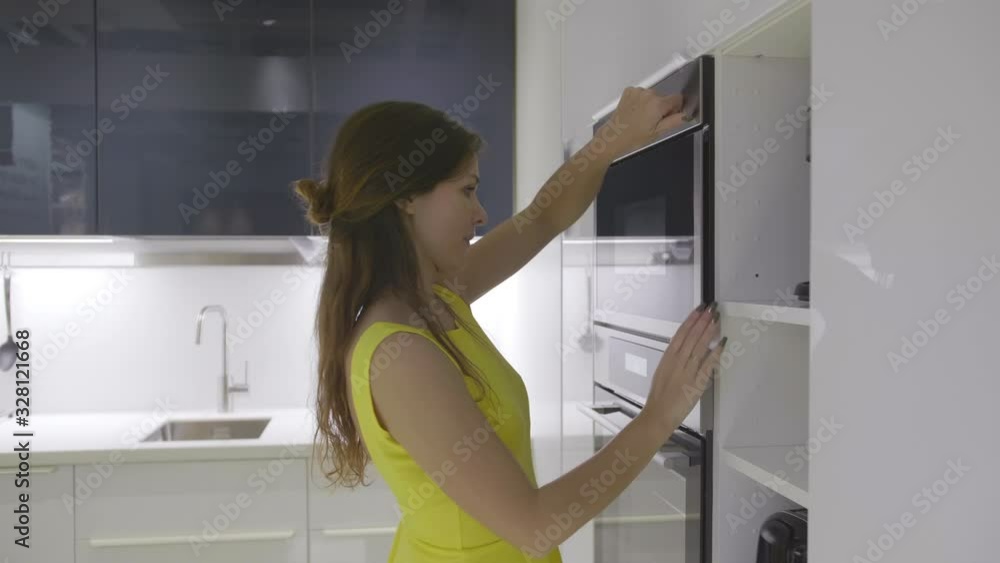 Young pretty woman open oven and take prepared dinner. Young pretty woman open oven and take prepared dinner.