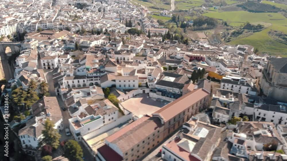 Aerial view of an ancient Spanish city Ronda in Andalucia. Drone flying over the famous bridge Puente Nuevo connecting the two parts of the Old Town, the Plaza de Toros (Bulls square) . Aerial view of an ancient Spanish city Ronda in Andalucia. Drone flying over the famous bridge Puente Nuevo connecting the two parts of the Old Town, the Plaza de Toros (Bulls square) .