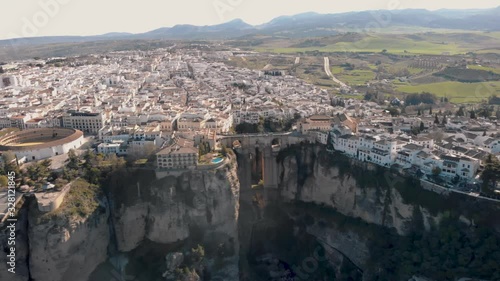 Aerial view of an ancient Spanish city Ronda in Andalucia. Drone flying over the famous bridge Puente Nuevo connecting the two parts of the Old Town, the Plaza de Toros (Bulls square) .