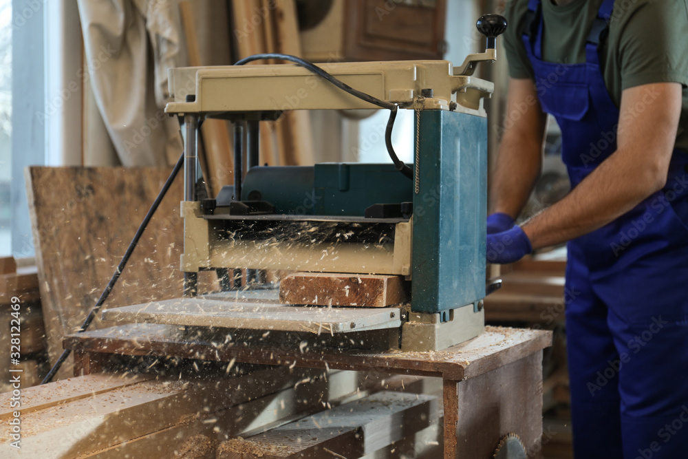 Professional carpenter working with grinding machine in shop, closeup Professional carpenter working with grinding machine in shop, closeup