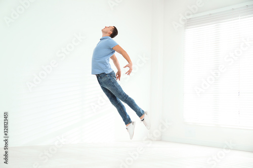 Fototapeta Naklejka Na Ścianę i Meble -  Handsome young man jumping indoors. Modern dance
