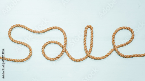 Inscription sale, made of rope, an invitation to the store for shopping at a discount. Isolated on a blue background.