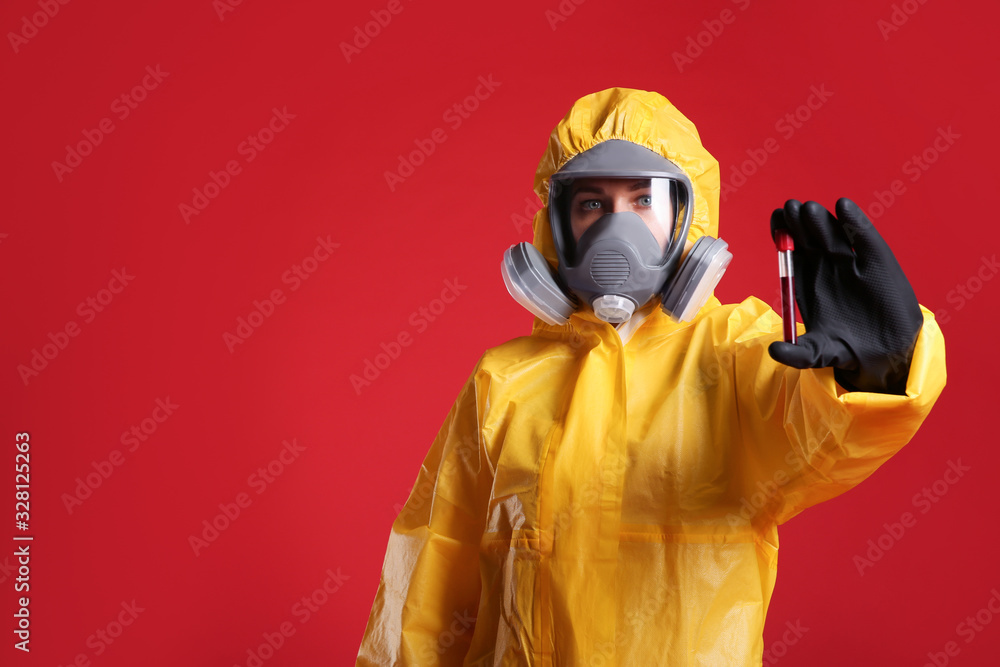 Woman in chemical protective suit holding test tube of blood sample on red background, space for text. Virus research