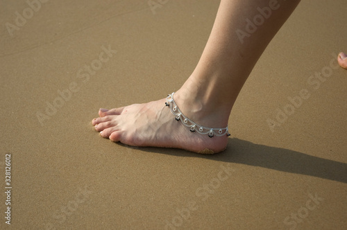 Canvas Print Closeup of a woman's legs with an anklet jewelry on the beach