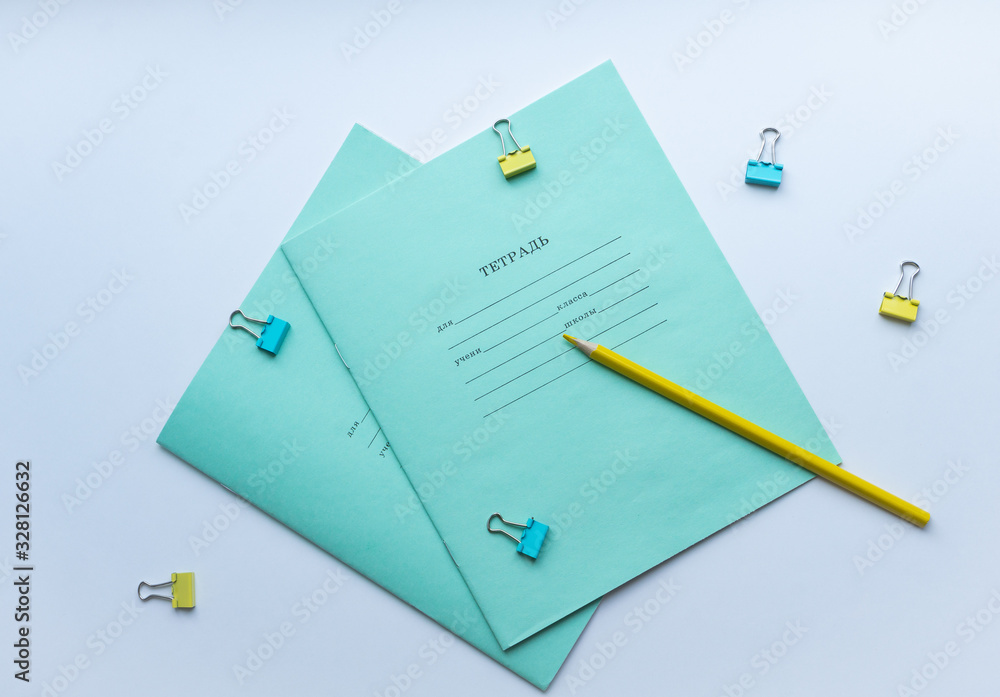 Top view of two pupils copybooks with form to sign in: name, surname, grade, etc. with yellow pencil and paper clips on white background. Concept of education, minimalism. Top view of two pupils copybooks with form to sign in: name, surname, grade, etc. with yellow pencil and paper clips on white background. Concept of education, minimalism.