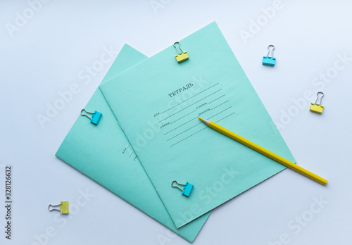 Top view of two pupils copybooks with form to sign in: name, surname, grade, etc. with yellow pencil and paper clips on white background. Concept of education, minimalism.