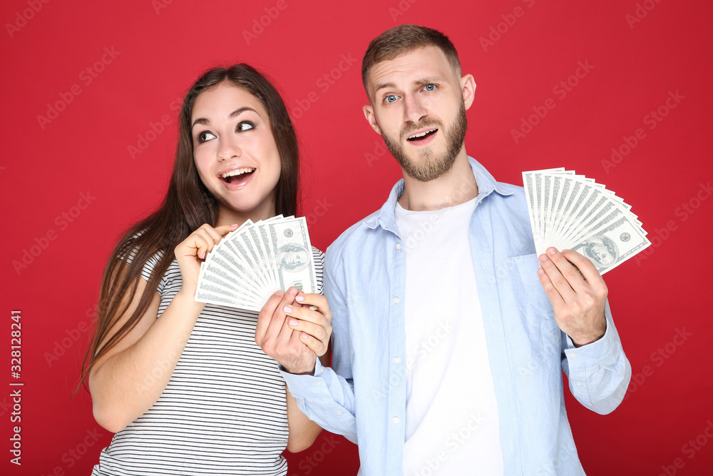 Happy young couple with dollar banknotes on red background Happy young couple with dollar banknotes on red background