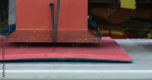 Factory production of synthetic products made of foam rubber, heavy press cuts foam blank of red color into flat hexagonal sponges, production of household goods, sponges for washing dishes, factory