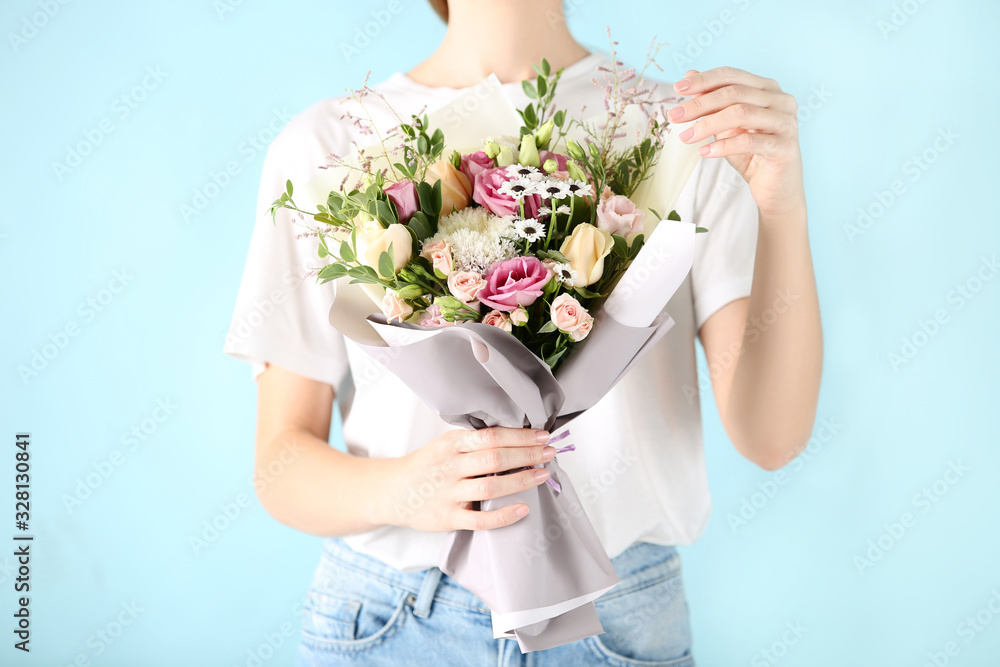 Female hand holding beautiful flower bouquet on blue background Female hand holding beautiful flower bouquet on blue background