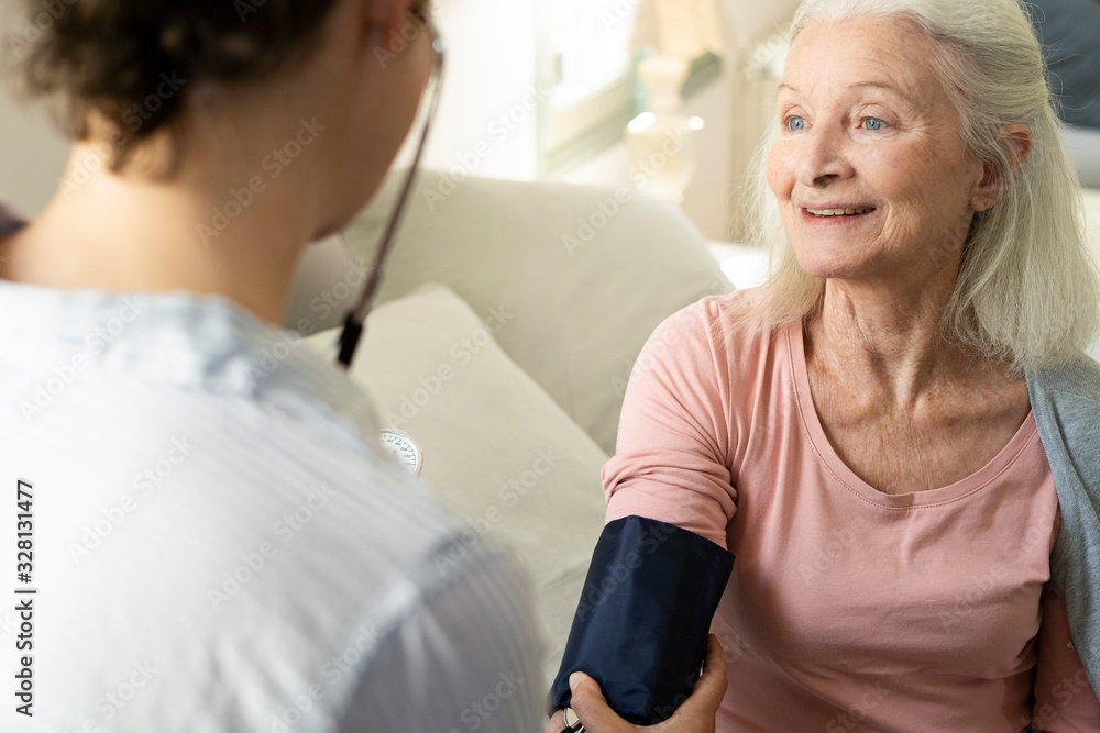 Home carer checking blood pressure of senior woman at nursing home Home carer checking blood pressure of senior woman at nursing home