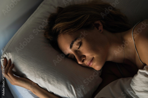 Close-up of young woman sleeping peacefully on bed in bedroom photo