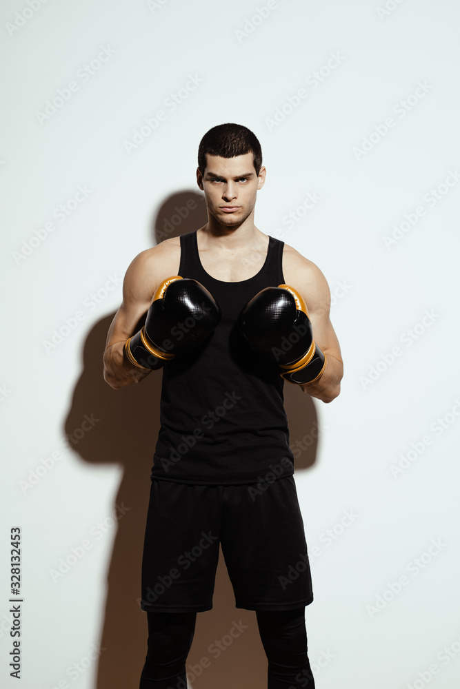 Tall attractive sportsman posing in boxing gloves over white background