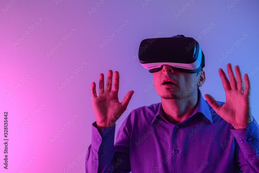 Man wearing virtual reality goggles. Studio shot, neon light background. Man using the virtual reality headset. Man wearing virtual reality goggles. Studio shot, neon light background. Man using the virtual reality headset.