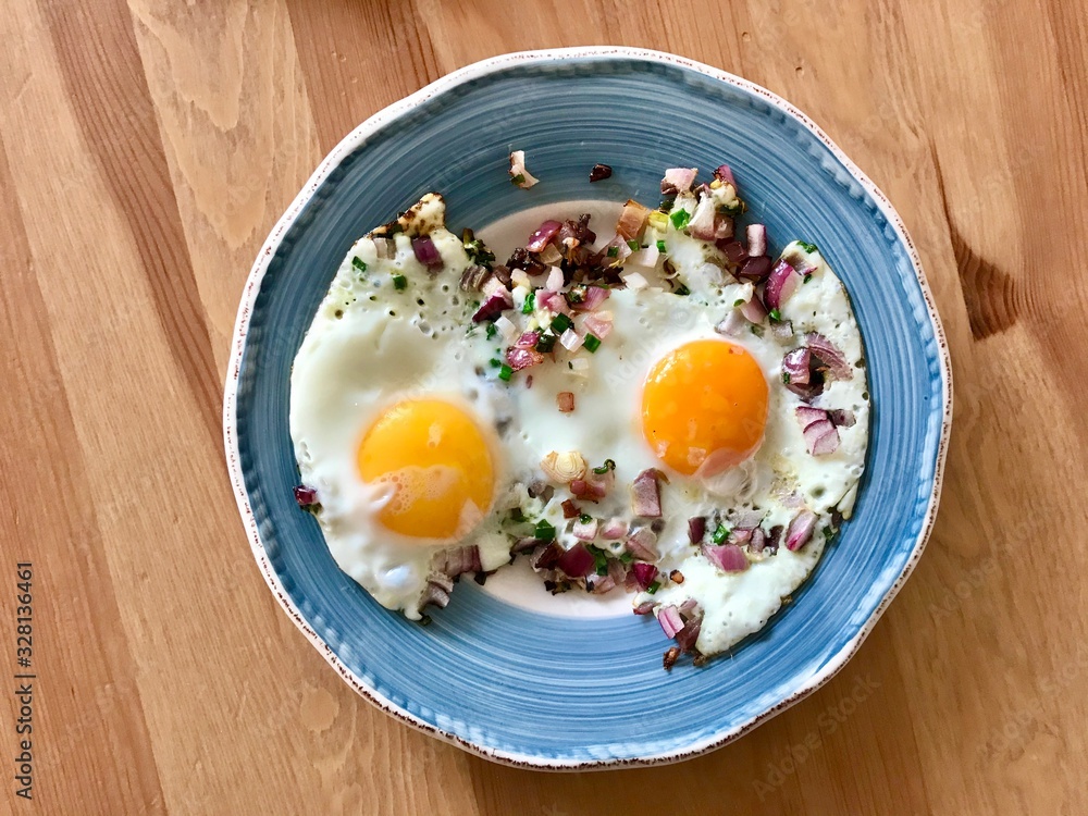 Sunny Side Up Fried Eggs with Red Onions and Chives for Breakfast in Plate. Organic Food Sunny Side Up Fried Eggs with Red Onions and Chives for Breakfast in Plate. Organic Food
