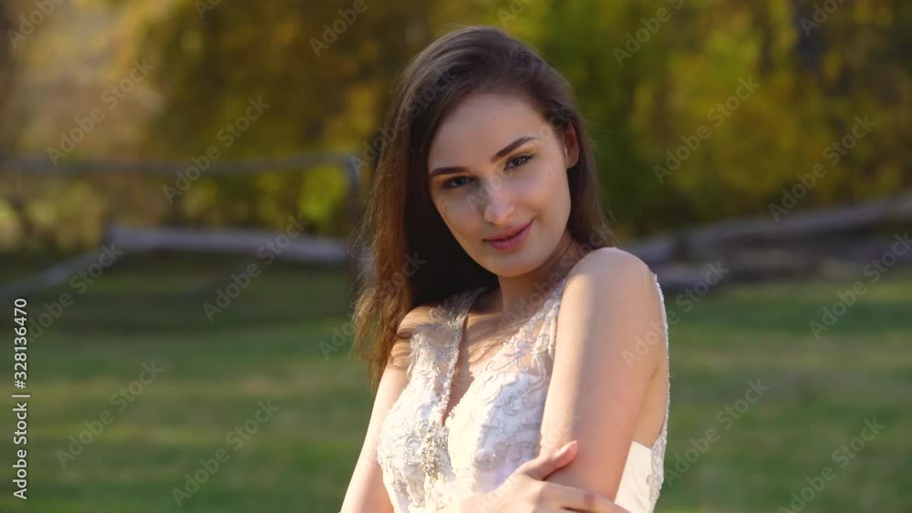 Portrait of beautiful brunette woman with long hair is posing in sunny rays at autumn park Portrait of beautiful brunette woman with long hair is posing in sunny rays at autumn park