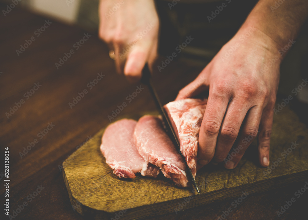 I cut pork with a knife on a wooden board