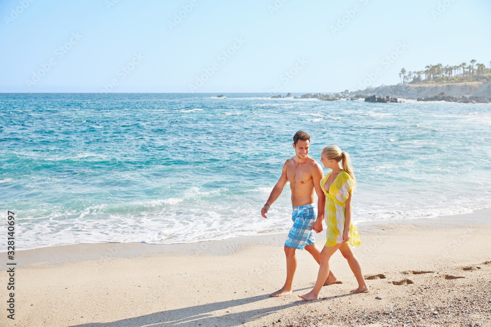 Romantic couple walking on the beach at a resort in Mexico Romantic couple walking on the beach at a resort in Mexico