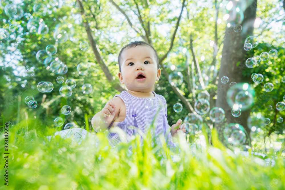 Dreamy Asian baby girl's portrait, smiling in bubbles in park Dreamy Asian baby girl's portrait, smiling in bubbles in park