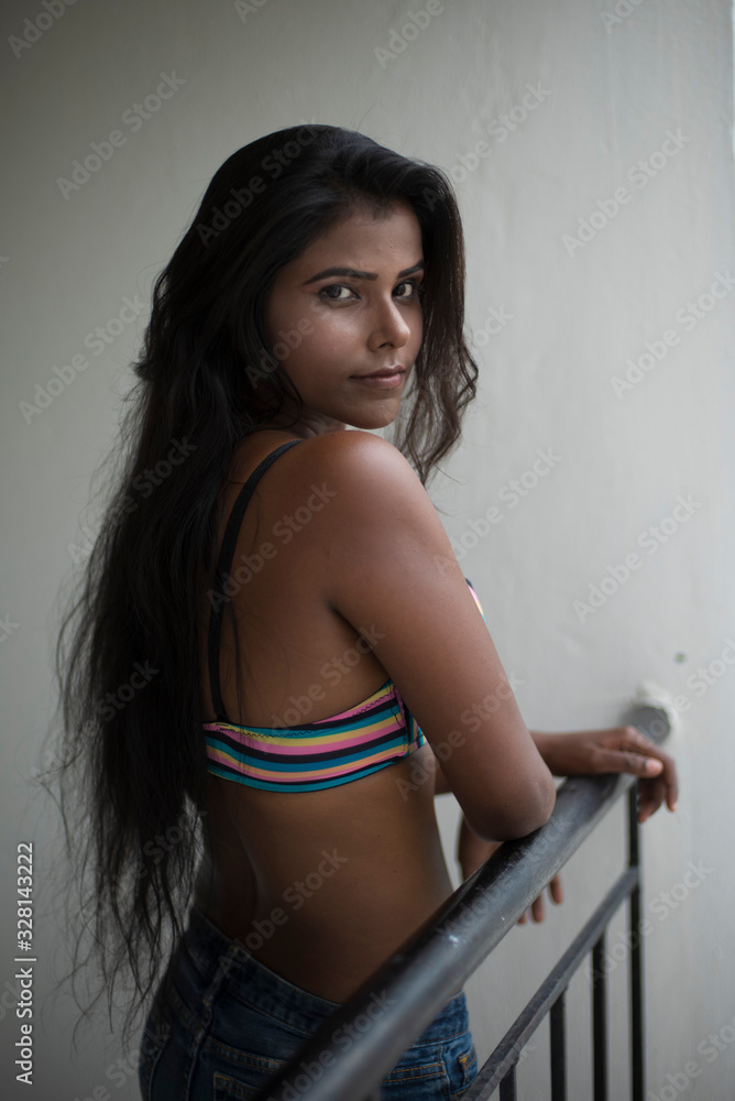 Accountant kapitalisme Poëzie Portrait of an young and beautiful dark skinned Indian Bengali woman in  colorful lingerie/bikini and hot pants posing in casual mood on a balcony  in white urban background. Boudoir photography. Stock Photo 