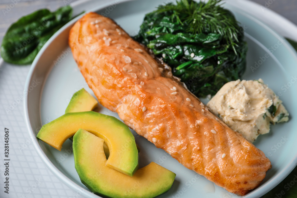 Tasty salmon with spinach and avocado on plate, closeup Tasty salmon with spinach and avocado on plate, closeup