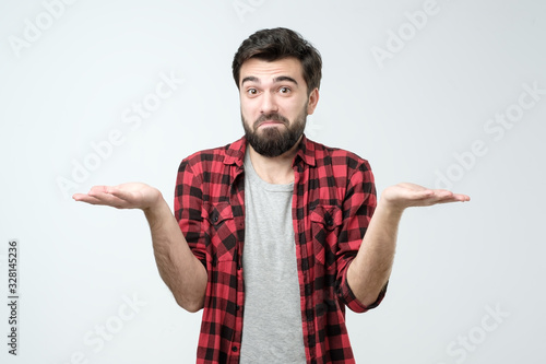Confused hispanic man giving I dont know gesture on white background.