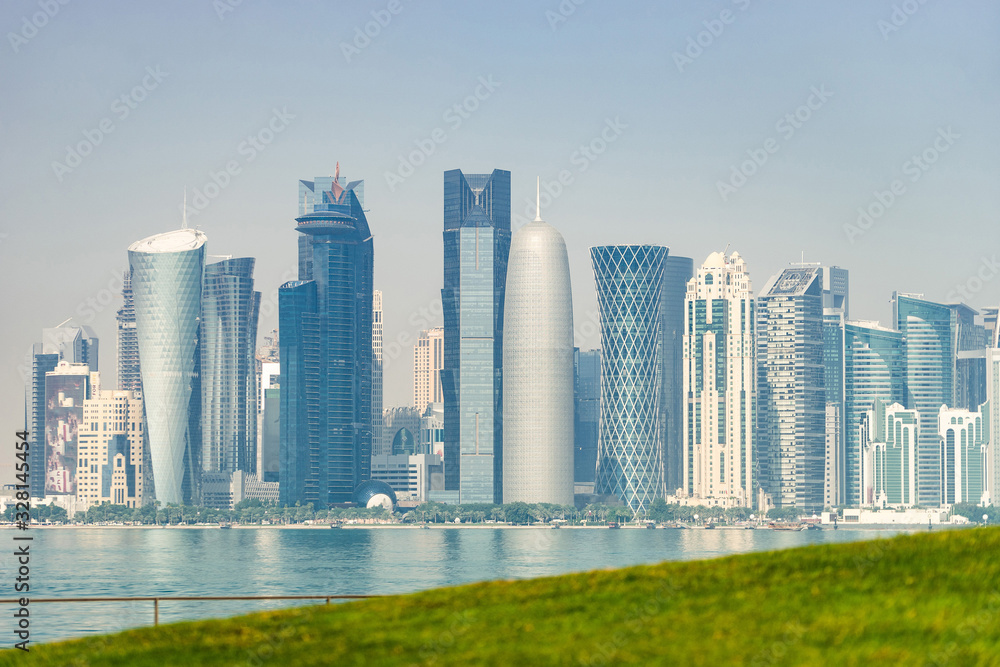 Fototapeta premium Panoramic view of modern skyline of Doha with green grass foreground. Concept of healthy environment