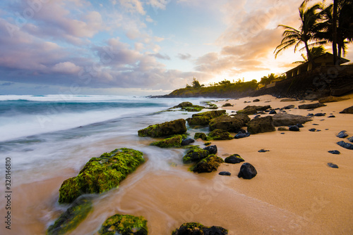 Awesome Colorful Sky at Sunset and Calm Ocean Water Coming on Sandy Beach Shore with Palm Trees Silhouette and Lush Greenery in Maui Hawaii