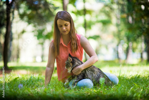 Portrait of a girl in the park with a maine coon cat.