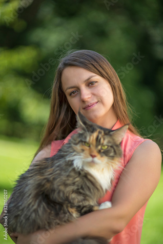 Portrait of a girl in the park with a maine coon cat.