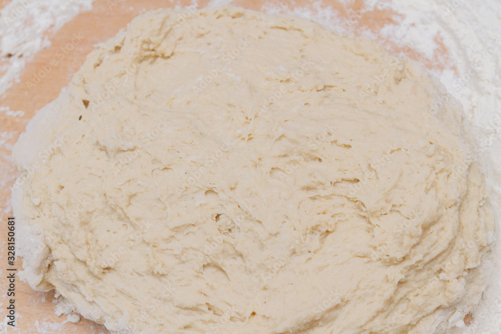 Kneading dough with flour on a wooden table at home