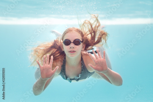 Girl underwater swimming pressing up against a glass pool wall photo